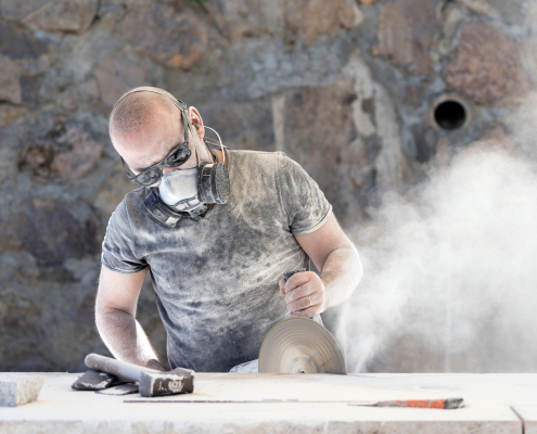 Worker cutting into stone with dust flying everywhere to spread awareness for silicosis