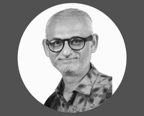 Black and white portrait of Dr Bhavesh Dave make wearing black glasses with a short beard wearing a collared shirt