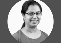 Black and White portrait of Dr Mamta Dave, female wearing glasses with long black hair tied up in a pony tail wearing a shirt