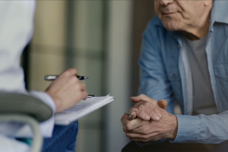 A healthcare professional consulting with a patient during a medical appointment, with notes being recorded on a clipboard.