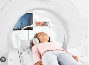 A child lying on an MRI scanner table with headphones on during a medical imaging examination.