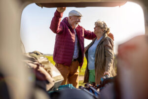 Two older adults standing beside an open vehicle, preparing for a road trip or outdoor outing.