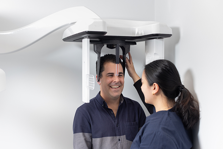 A patient undergoing a panoramic dental X-ray while a healthcare professional positions the imaging equipment.