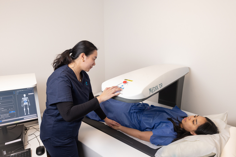 A patient lying on a scanning table during a DEXA bone density scan as a healthcare professional monitors the procedure.